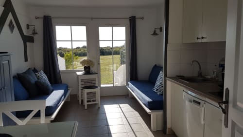 Appartement moderne Locations Loc'Maria, Belle Île, avec deux lits, kitchenette et vue sur mer par portes vitrées