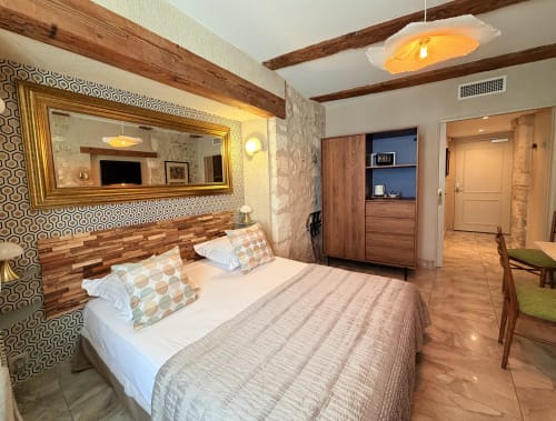 Modernes Hotelzimmer im Hôtel La Suite in Villeneuve-lès-Avignon mit Queensize-Bett, Holzbalken, vergoldetem Spiegel und Stadtblick