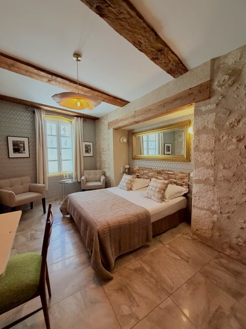 Chambre A à l'Hôtel La Suite à Villeneuve-lès-Avignon : chambre élégante aux poutres apparentes, vue sur la ville et équipements modernes