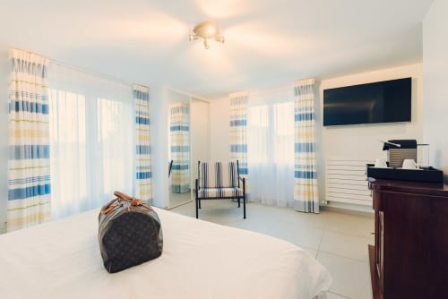 Chambre lumineuse du Clos Céleste B&B en Normandie avec rideaux rayés, TV écran plat et décoration d'inspiration côtière