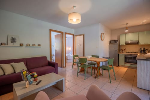Salon moderne de la Residence Guddelmoni à Propriano avec cuisine, table à manger, canapé bordeaux et vue sur le jardin