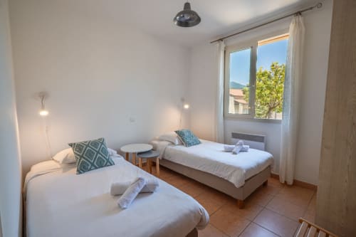 Chambre twin avec draps blancs et vue sur le jardin à la villa Residence Guddelmoni à Propriano