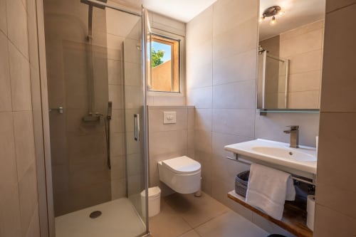 Salle de bain moderne à la villa Guddelmoni, Propriano. Douche vitrée, toilettes murales, lavabo et lumière naturelle