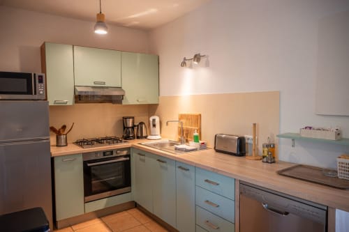 Cuisine moderne avec armoires bleu ciel, comptoirs en bois et appareils inox à la villa Guddelmoni