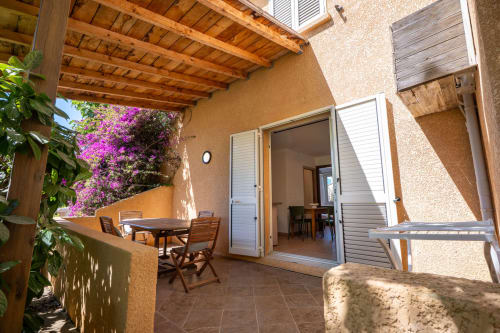 Terrasse privée de la villa Guddelmoni à Propriano avec pergola en bois, bougainvillée violette et vue sur le jardin