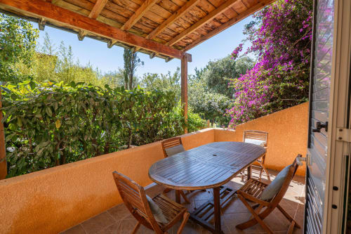 Terrasse ombragée avec table à manger à la villa Guddelmoni de Propriano, dominant des jardins luxuriants aux fleurs magenta
