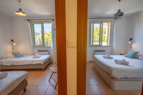 Chambre de villa moderne à la Résidence Guddelmoni à Propriano avec lits jumeaux, poutres en bois, luminaires suspendus et vue sur le jardin
