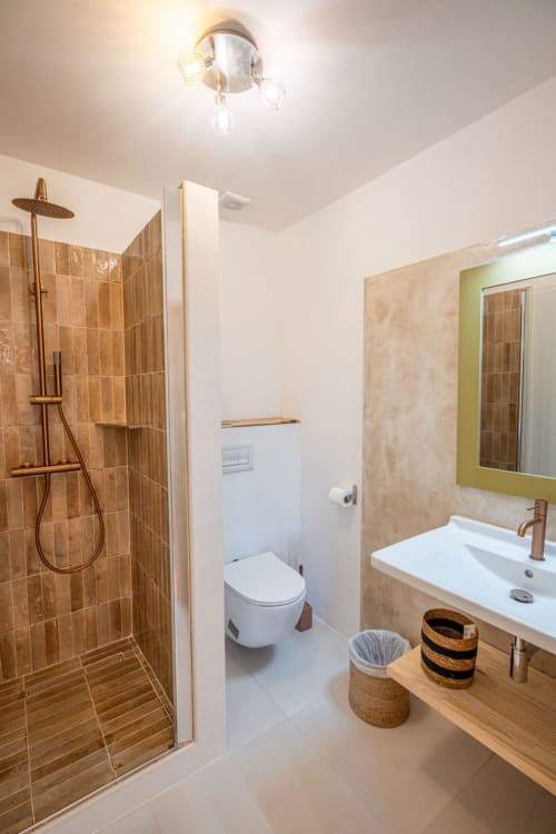 Salle de bain moderne à la villa Guddelmoni à Propriano avec douche à l'italienne, lavabo blanc, toilettes et miroir encadré vert