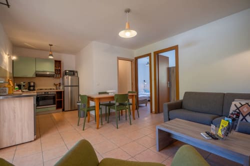Espace de vie en open-plan à la Résidence Guddelmoni, Propriano, avec cuisine, table à manger, canapé gris et terrasse