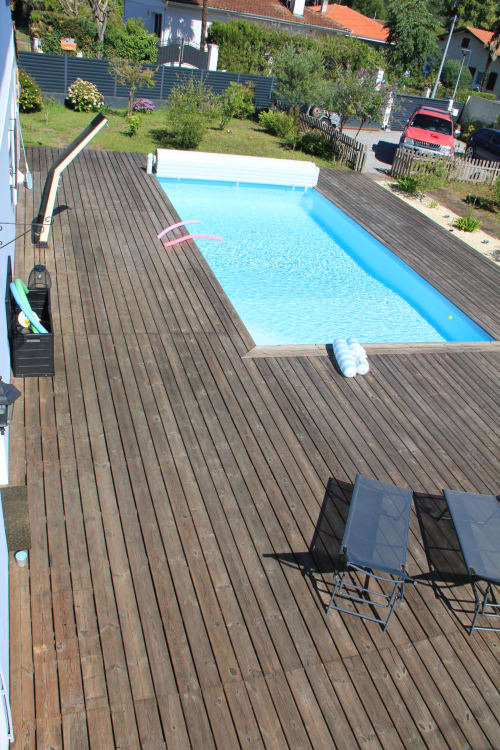 Piscine rectangulaire aux eaux bleues avec terrasse en bois du gîte La Pause Landaise à Magescq, France