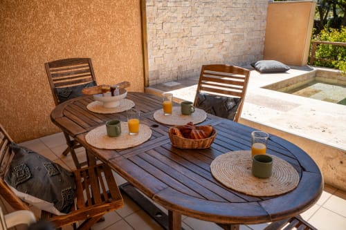 Terrasse extérieure de la villa Residence Guddelmoni avec table à manger en bois, chaises, petit-déjeuner avec jus d'orange et