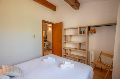 Chambre de la villa Guddelmoni à Propriano avec lit blanc, étagères en bois et vue sur le jardin