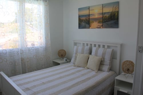Chambre lumineuse au gîte La Pause Landaise à Magescq avec literie rayée, tête de lit blanche, tableau coucher de soleil et
