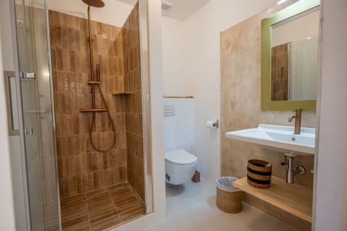 Salle de bain moderne de la villa à Propriano avec douche carrelée marron, lavabo blanc, miroir et toilettes