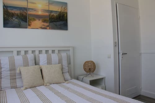 Chambre lumineuse avec literie rayée, décoration murale thème plage et lampadaire en rotin au cottage Le Grand Bain à La Pause Landaise