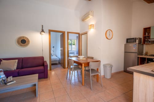 Séjour ouvert dans la villa de Propriano avec canapé violet, table à manger, kitchenette et accès aux chambres