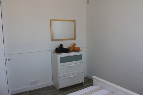 Chambre du gîte Le Grand Bain à La Pause Landaise avec commode blanche, miroir à cadre bois et parquet foncé