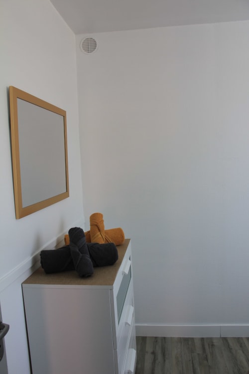 Coin minimaliste de chambre avec miroir en bois et serviettes roulées au gîte Le Grand Bain, La Pause Landaise