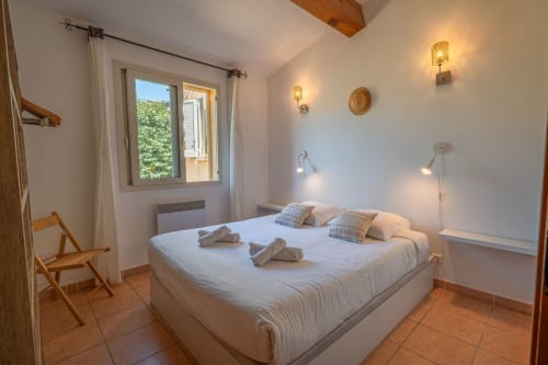 Chambre lumineuse avec lit queen-size, poutres en bois, vue sur le jardin et équipements modernes à la villa Residence Guddelmoni