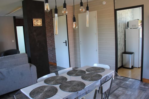 Cuisine moderne de La Pause Landaise avec table à manger, luminaires suspendus et accès à la vue sur piscine à Magescq, France