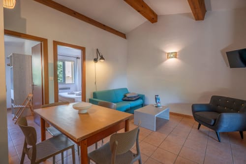Villa moderne avec salon, table de salle à manger, canapé turquoise, télévision et poutres en bois à la Résidence Guddelmoni, Propriano
