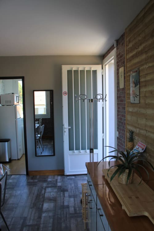 Coin cuisine-séjour du cottage Le Grand Bain à La Pause Landaise avec porte blanche, mur de brique et électroménagers modernes