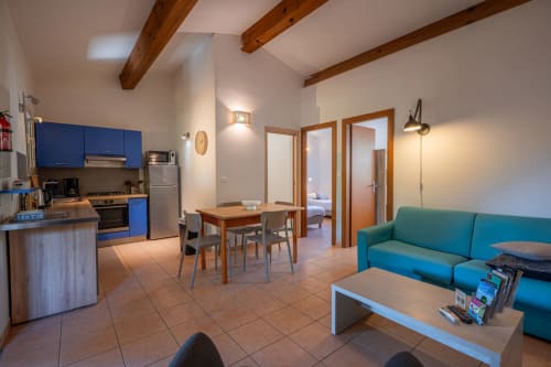 Espace de vie ouvert de la villa Guddelmoni à Propriano avec cuisine bleue, table à manger, canapé turquoise et éléments en bois