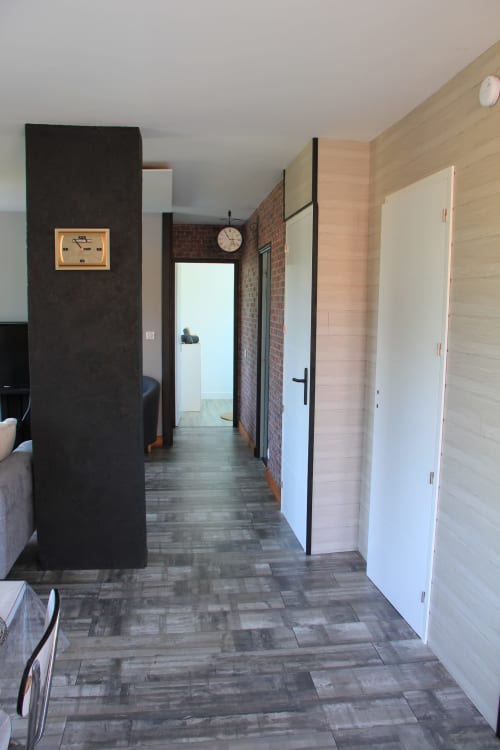 Couloir moderne du gîte Le Grand Bain à La Pause Landaise avec mur d'accent sombre, brique et portes blanches