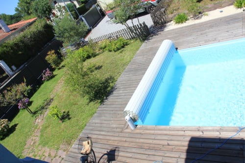 Piscine étincelante avec bâche roulante bleue et terrasse en bois au gîte La Pause Landaise à Magescq, France