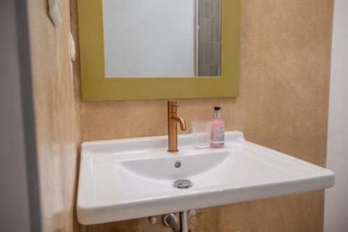 Lavabo moderne avec robinetterie bronze, miroir et articles de toilette à la villa Guddelmoni de Propriano