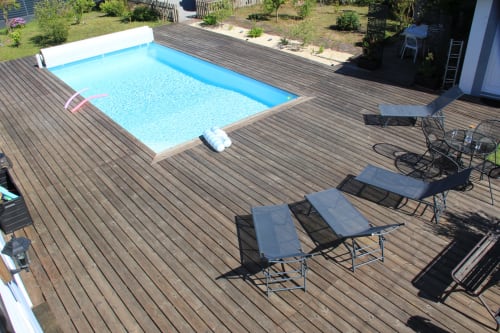 Piscine rectangulaire bleue avec chaises longues sur terrasse en bois à la gîte La Pause Landaise, Magescq
