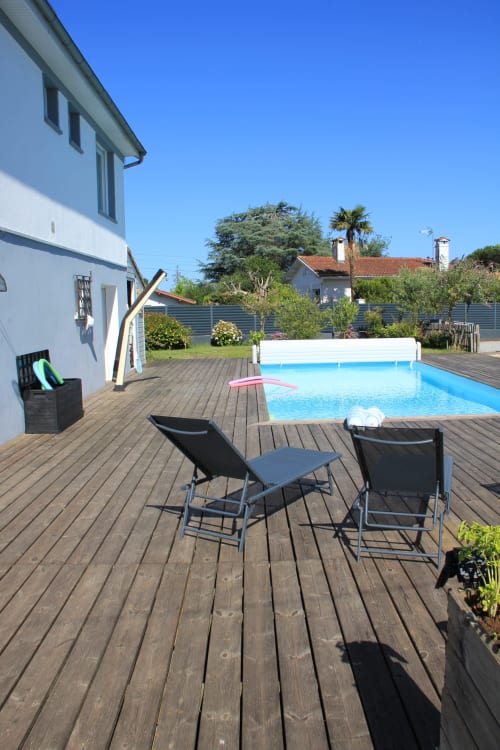 Terrasse piscine du cottage Le Grand Bain avec transats, piscine bleue et maison blanche à La Pause Landaise à Magescq, France