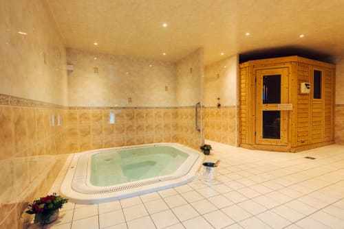 Salle de spa luxueuse au Clos Céleste avec bain à remous chauffé, cabine sauna en bois et éclairage ambiant chaleureux.