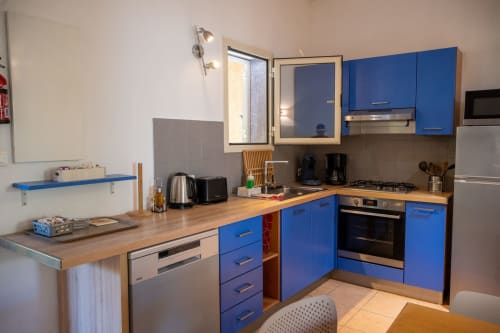 Cuisine moderne bleue avec comptoirs en bois, électroménagers en acier inoxydable et salle à manger à la Mini Villa 5, Residence