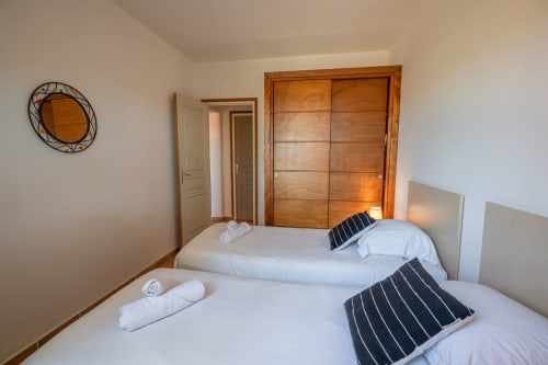 Chambre twin avec lits blancs et armoire en bois à la Résidence Guddelmoni, Propriano