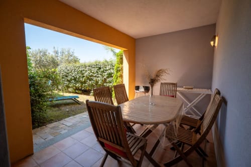 Terrasse couverte avec table à manger et chaises donnant sur le jardin de la Résidence Guddelmoni, Propriano