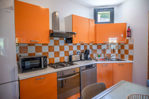 Cuisine orange vif et blanche à la Résidence Guddelmoni, Propriano, avec crédence à carreaux, cuisinière gaz et style moderne
