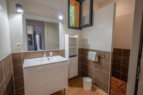 Salle de bain moderne avec vanité blanche, accents en carrelage marron et douche, Résidence Guddelmoni, Propriano