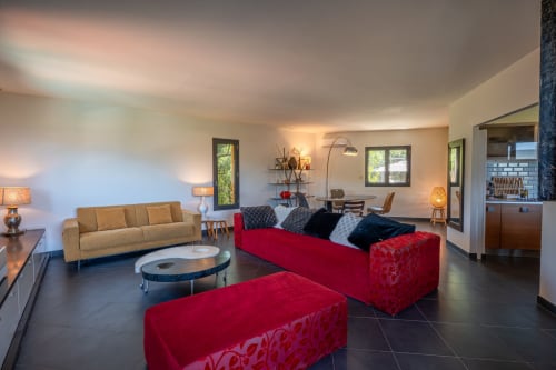 Séjour moderne avec canapés rouges, causeuse beige et vue mer dans l'appartement de Propriano à la Résidence Guddelmoni