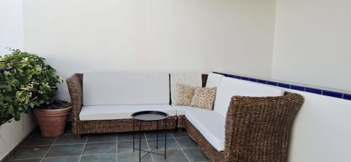 Área de descanso con muebles de ratán tejido y cojines blancos en Villas del Mar Puerto Calero, con planta en maceta y mesa auxiliar moderna