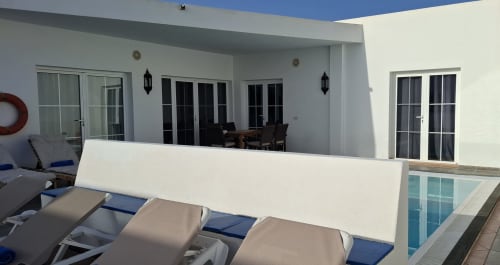Patio de villa moderna con tumbonas, estructura de sombra blanca y puertas de cristal en Villas del Mar Puerto Calero