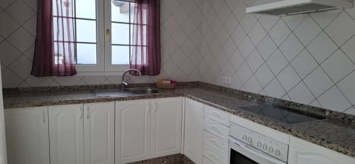 Cocina moderna en Villa 6 de Villas del Mar, Puerto Calero con encimeras de granito, gabinetes blancos y salpicadero de azulejos
