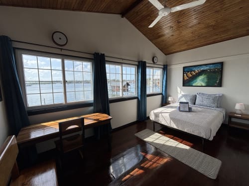 Habitación luminosa frente al mar en BarrBra BnB en Bocas del Toro con vistas a la bahía, techo de madera oscura, cama queen y escritorio.