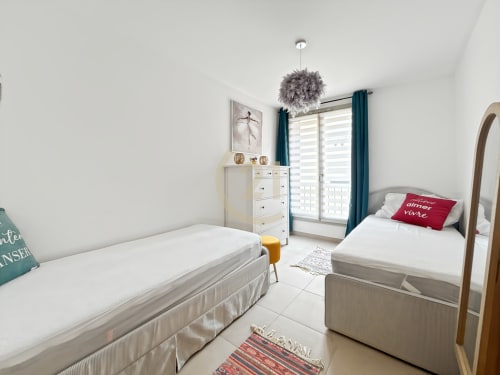 Chambre twin lumineuse de l'appartement Citadella, Calvi avec lits blancs, luminaire gris pendant et équipements modernes incluant TV et