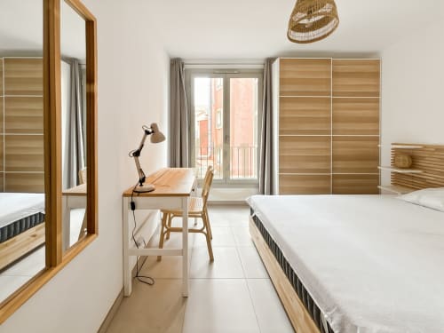 Chambre moderne avec mobilier en bois, deux lits, bureau et vue sur le balcon de l'appartement à Calvi