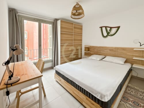 Chambre moderne de l'appartement de Calvi avec lit en bois, bureau, vue sur la balcon ville et mobilier contemporain