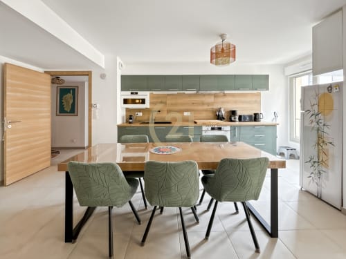Cuisine ouverte et salle à manger contemporaine à Calvi avec armoires vert sauge, table en bois et mobilier actuel