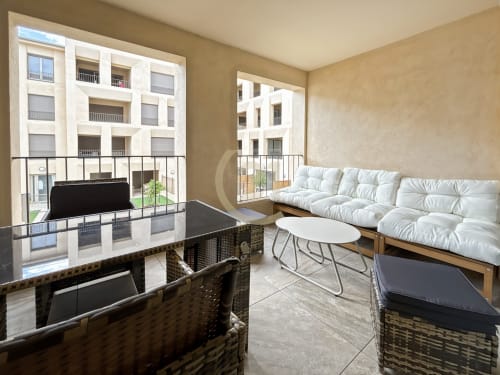 Salon moderne d'un appartement avec canapé blanc, vue sur la ville et balcon surplombant L'Île-Rousse