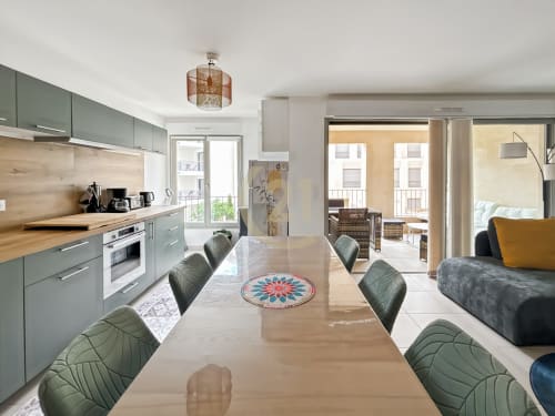 Appartement moderne ouvert à Calvi avec table à manger, cuisine verte, salon et vue sur la ville