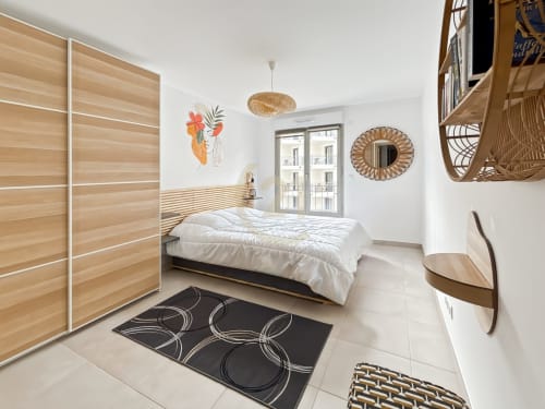 Chambre moderne de l'appartement de Calvi avec armoire bois, literie blanche, portes vue mer et accents de décor côtier